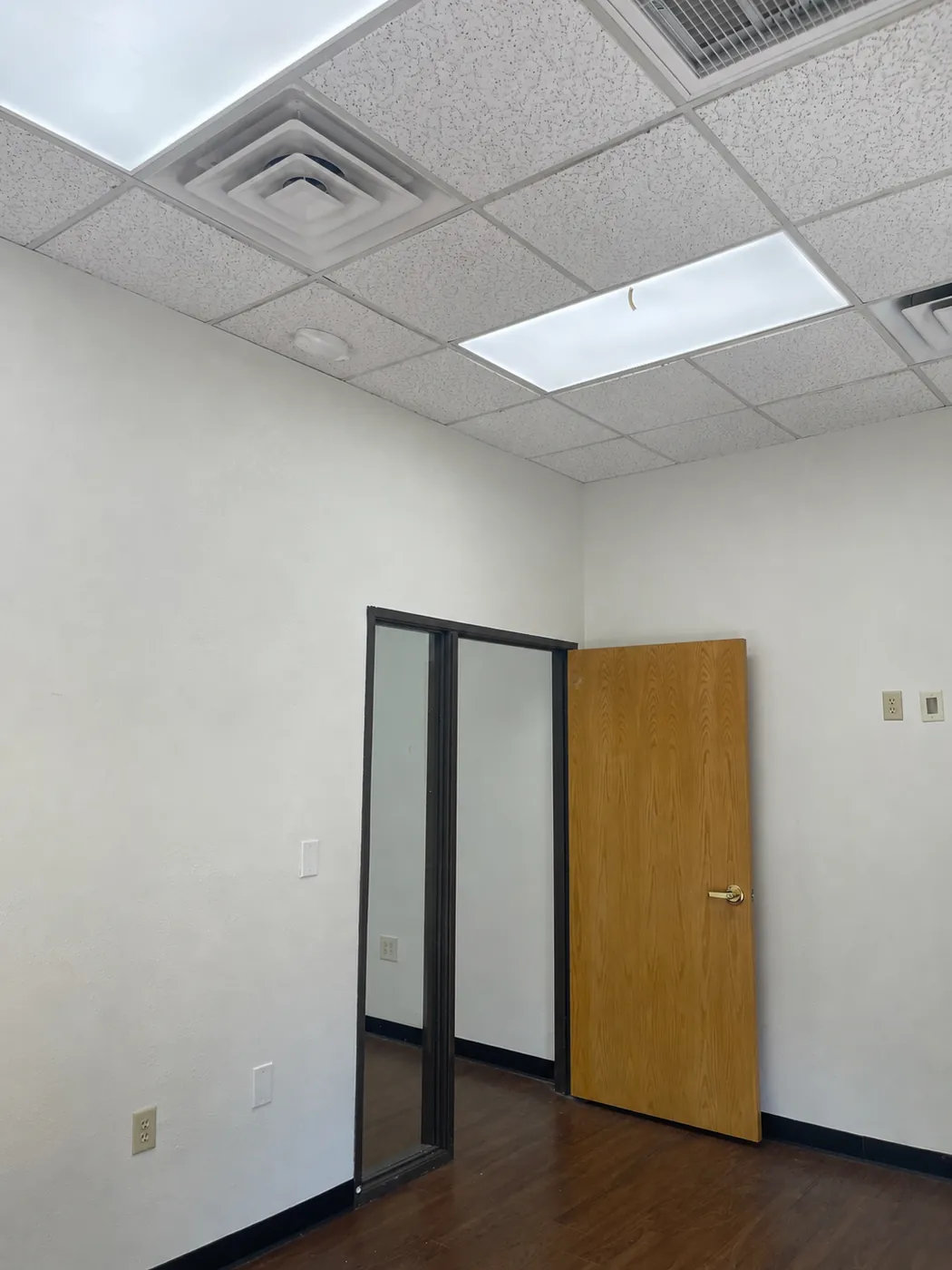 Private office inside Suite 100B with glass sidelight, fresh paint, and wood-look flooring